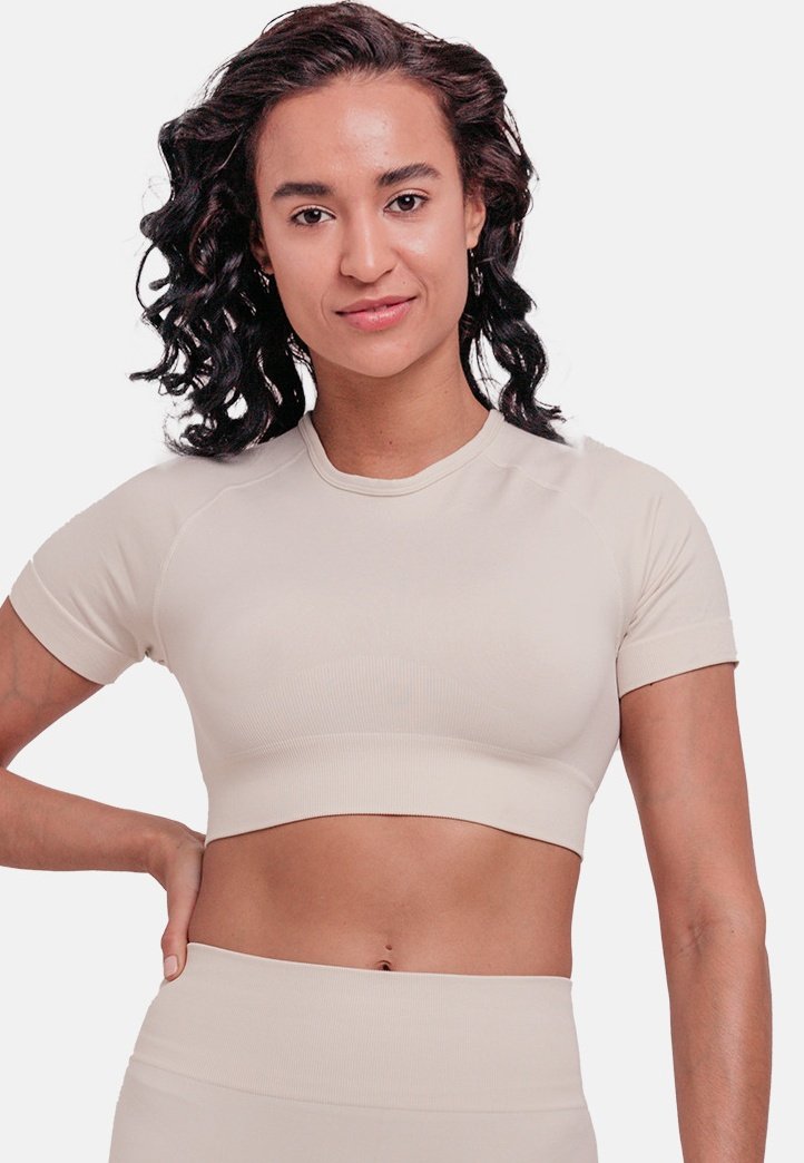 Beige cropped athletic top with short sleeves, ribbed texture, and a round neckline. The design features fitted, smooth fabric.