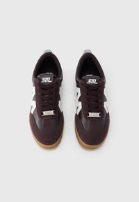 Καφέ αθλητικά παπούτσια με λευκές λεπτομέρειες, διαθέτουν επάνω μέρος από σουέντ και δέρμα, στρογγυλή μύτη και καφέ σόλα από καουτσούκ. Σχεδίαση με κορδόνια και λογότυπο.