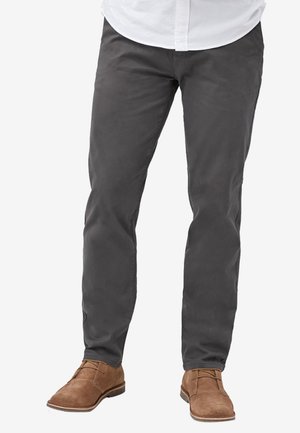 Pantalon en coton gris avec une coupe ajustée, devant plat et design à cinq poches. Assorti avec des chaussures en daim marron clair.