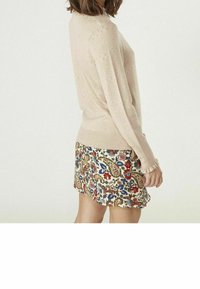 Ljust rosa, strukturerad stickad tröja med långa ärmar, i kombination med en blommönstrad kjol med röda, blå och gröna detaljer.