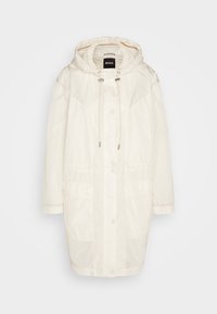 Parka longue à capuche de couleur blanc cassé avec boutons-pression sur le devant, capuche avec cordon de serrage, deux poches avant et étiquette de la marque BOSS à l'intérieur du col.