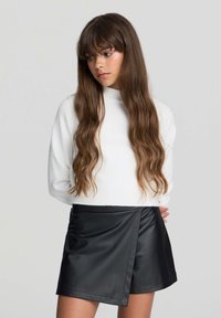 Biała, długosleeve'owa dzianinowa sweter zestawiona z czarną spódnicą z sztucznej skóry z zapięciem na skos i miękką teksturą.