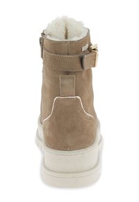 Stivaletto alla caviglia in suede beige con fodera in pelliccia artificiale, dotato di una cinghia laterale con una fibbia dorata e una suola bianca texturizzata.