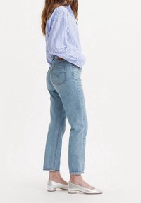 Ljusblå högmidjade jeans med avslappnad passform, som har en klassisk bakfickedesign. Kombineras med en blå och vit randig skjorta och silvriga ballerina-skor.