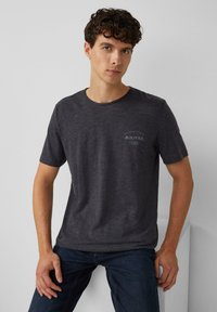 Czarnoszary T-shirt z krótkim rękawem, wykonany z miękkiego materiału, z nadrukowanym logo na lewej stronie klatki piersiowej. Prosty fason z okrągłym dekoltem, w regularnym kroju.