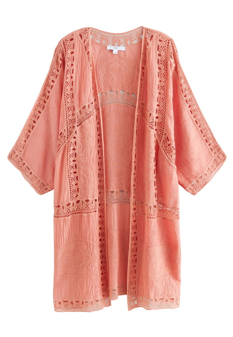 Persikanvärinen kimonomallinen neuletakki, jossa on lyhyet hihat, pitsireunus, teksturoitu kangas ja yksityiskohtaiset kirjailut koko pinnalla.