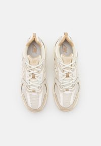 Valkoiset verkkokangas- ja nahkaurheilukengät, joissa on beigejä yksityiskohtia, teksturoidut päällysteet, nauhat ja pehmustettu kaulus mukavuutta varten.