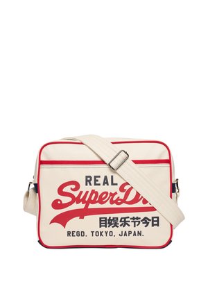 Sac bandoulière rectangulaire beige avec bordure rouge et sangle ajustable, arborant le texte "Real SuperDry" et des caractères japonais à l'avant.