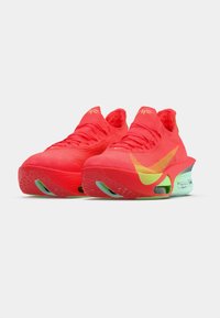 Czerwone buty sportowe z textured knit górą, jaskrawymi akcentami i charakterystyczną podeszwą z zielonymi detalami.