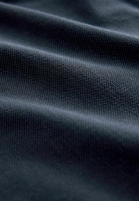 Tela texturizada azul oscuro con un patrón tejido, que muestra una superficie suave, ligeramente reflectante y pliegues suaves.