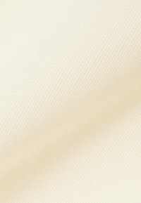 Acercamiento de una tela fina, de color crema, tejida de manera apretada, con sutiles pliegues diagonales y una textura suave.