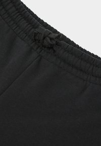 Schwarze Baumwoll-Sweatpants verfügen über einen elastischen Bund mit einer Kordel zum Verstellen. Der Stoff wirkt glatt mit einem leichten Glanz.