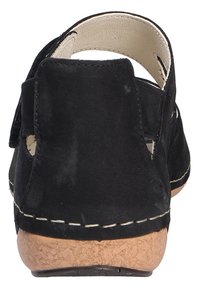 Zwarte suède schoenen met een kurken tussenzool. Kenmerken zijn uitsparingen aan de zijkanten en een afgeronde achterkant, met gestikte details langs de rand.