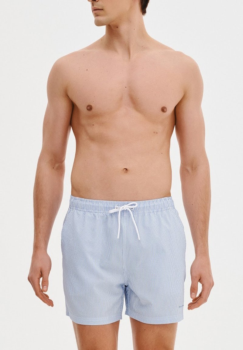 Niebieskie i białe spodenki kąpielowe w paski z elastycznym paskiem w talii i sznurkiem do regulacji. Lekki materiał, długość powyżej kolana.