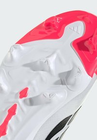 Λευκή σόλα αθλητικού παπουτσιού με υφή στην επιφάνεια, διαθέτει έντονες ροζ αποχρώσεις και πολυκατευθυντικά καρφιά για καλύτερη πρόσφυση.