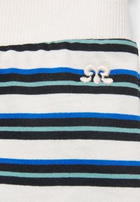 Tissu tricoté avec des rayures horizontales en blanc, noir, bleu et vert, avec un petit symbole blanc brodé sur fond blanc.