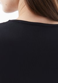 Schwarzes, eng anliegendes T-Shirt mit glatter Textur, das ein einfaches Design und einen weiten Halsausschnitt zeigt. Der Stoff wirkt dehnbar und weich.