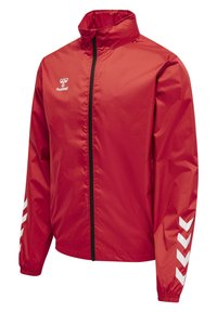 Rote Windbreaker-Jacke mit Reißverschluss vorne, hohem Kragen und elastischen Bündchen. Mit weißen Chevron-Streifen an den Ärmeln und einem Logo auf der Brust.