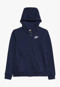 Námořnická modrá mikina na zip vyrobená z měkké tkaniny, která má přední kapsu, kapuci na stažení a bílé logo Nike na levém prsu.