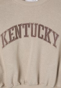 Felpa beige con la scritta "KENTUCKY" in grandi lettere ricamate di colore marrone. Il design include un collo a costine e un orlo elastico.