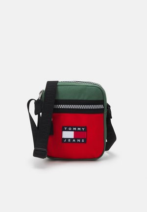 Kleine rechteckige Umhängetasche mit grünen und roten Paneelen, schwarzem verstellbarem Riemen, Frontreißverschlusstasche und Tommy Jeans Logo-Patch.