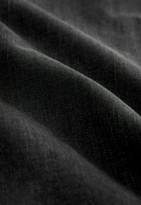 Must mustri kangas tekstuuriga pinnaga, millel on õrnad diagonaalliinid ja pehme, kergelt läikiv lõpetamine. Kortsud loovad sügavust.