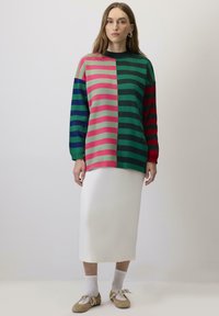 Multikleurige gestreepte trui in groen, roze en blauw, met een relaxed fit en lange mouwen, gecombineerd met een witte midi rok.