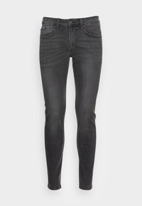 Jeans skinny de mezclilla negra con una textura suave, cinco bolsillos y cierre de cremallera. Presenta un ligero desgaste y un diseño clásico de 5 botones.