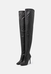 Botas de tacón alto de imitación de cuero negro hasta el muslo, con textura de cocodrilo, punta afilada y tacón de aguja delgado.