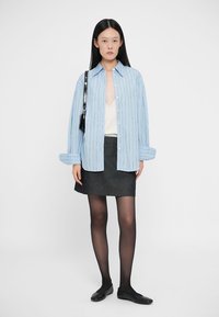 Camicia a righe blu chiaro, top bianco, gonna di jeans nera, collant trasparenti neri e ballerine nere. Design semplice con colori a contrasto.