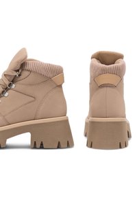 Béžové členkové topánky s textúrovaným pleteným golierom, okrúhlou špičkou a hrubou, zúženou gumovou podrážkou. Majú šnurovanie a decentné logo.