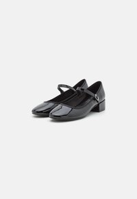 Black patent leather Mary Jane shoes with a slight block heel, featuring adjustable strap and rounded toe design. Smooth texture.
