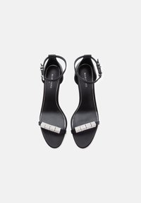 Černé sandály na podpatku s elegantním designem, které mají pásek zdobený kamínky a sponou kolem kotníku, vyrobené z hladkých materiálů.