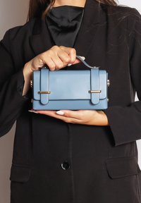 Borsa a mano in finta pelle blu con forma rettangolare, con dettagli in oro e doppi manici superiori. Texture liscia e design elegante.