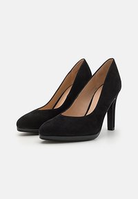 Black suede high-heeled pumps with a pointed toe, curved sides, and a shiny black platform accent, featuring a smooth interior lining.