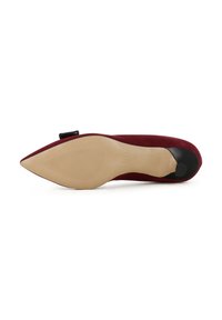 Scarpa con tacco alto in suede rosso, punta affusolata, accenti neri sul tacco, suola texturizzata e un fiocco decorativo su un lato.