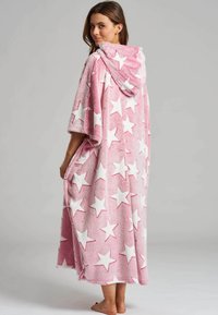 Rosarutig poncho med huva och ett vitt stjärnmönster, med korta ärmar, en plyschig textur och sidofickor. Längden når till mitten av vaden.