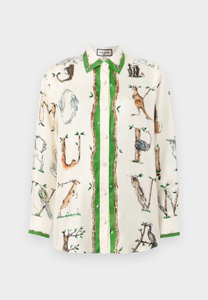 Chemise blanche à manches longues avec bordure verte, ornée d'illustrations d'animaux et de branches d'arbres formant des lettres dans un motif fantaisiste.