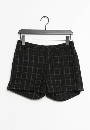 Pantaloni neri corti con un motivo a griglia, realizzati in tessuto testurizzato, con tasche frontali e un leggero risvolto, appesi a un appendiabiti nero.