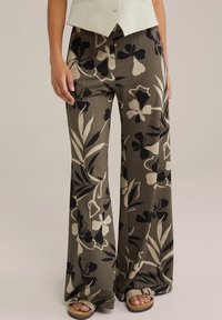 Lahkotne, vzorčaste široke hlače v zemeljskih tonih olivno zelene, črne in kremne. Teksturovan material s cvetličnimi in listnatimi vzorci.