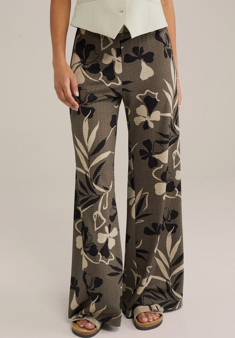 Lahkotne, vzorčaste široke hlače v zemeljskih tonih olivno zelene, črne in kremne. Teksturovan material s cvetličnimi in listnatimi vzorci.