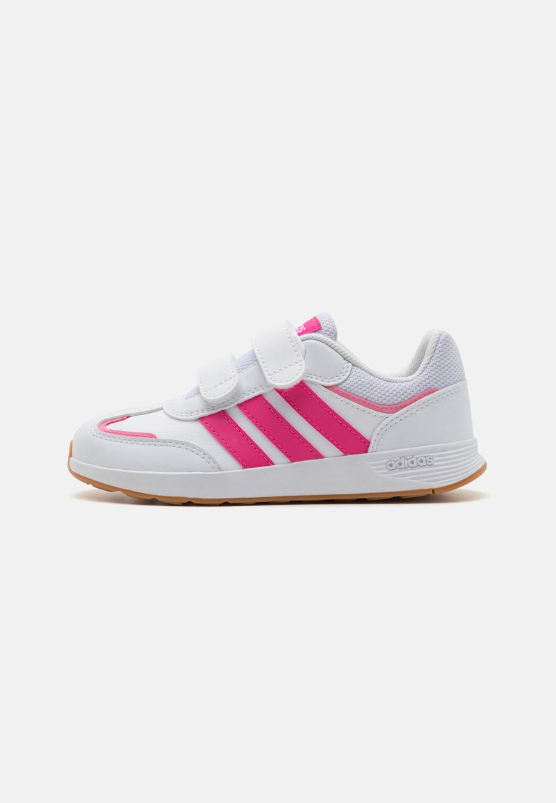 Zapatilla deportiva blanca con rayas rosas, correas de velcro y suela de goma. Presenta detalles de malla y un diseño de punta redondeada.