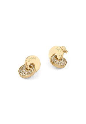 Orecchini in tono oro caratterizzati da un design attorcigliato con una superficie testurizzata e cristalli trasparenti scintillanti incorporati nella parte inferiore. Marca 'GUESS' visibile.