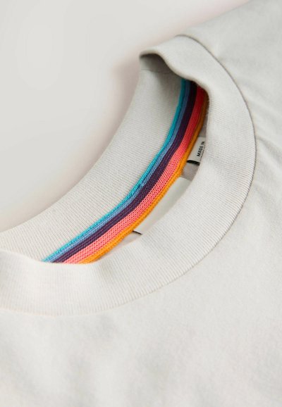 Hvid t-shirt med rund hals og synligt flerfarvet stribet stof (orange, pink, lilla, blå) langs den indvendige krave-søm.