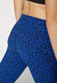 Μπλε κολάν με λεοπάρ σχέδιο και εφαρμοστή γραμμή, που διαθέτουν ομαλή υφή και διακριτές ραφές κατά μήκος της ζώνης και των ποδιών.