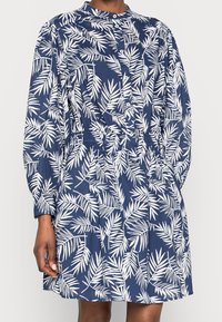 Robe bleu marine avec motif de feuilles blanches, boutonnée à l'avant, à manches longues et taille élastique. Fabriquée en tissu léger avec une coupe décontractée.