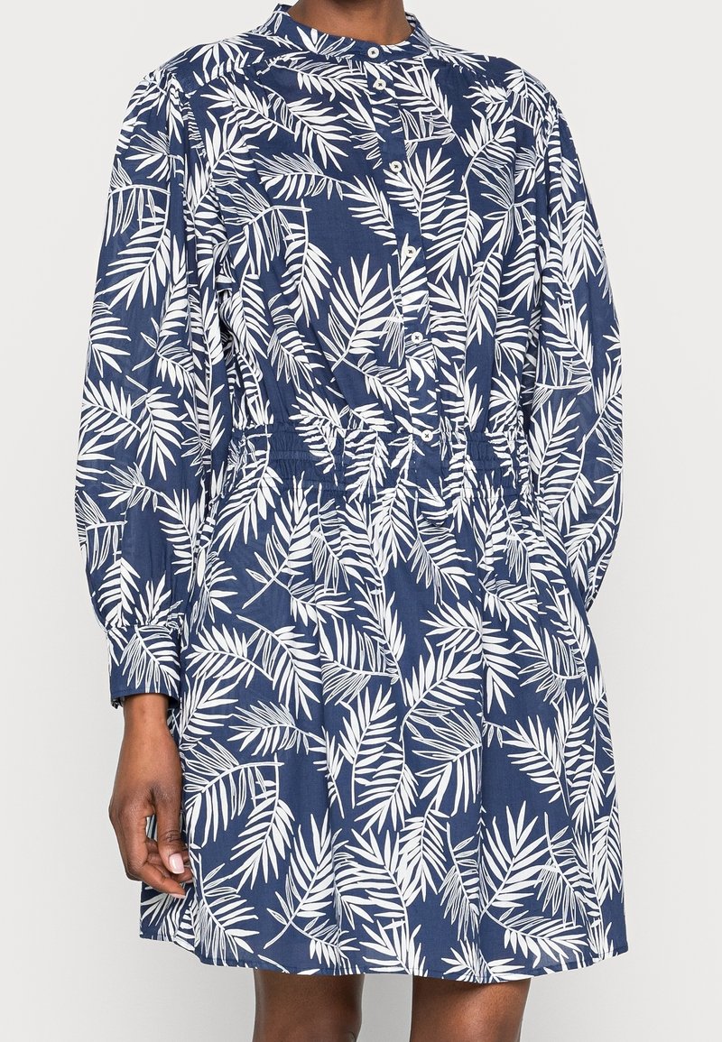 Robe bleu marine avec motif de feuilles blanches, boutonnée à l'avant, à manches longues et taille élastique. Fabriquée en tissu léger avec une coupe décontractée.