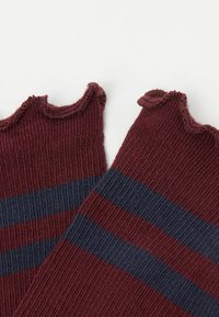Burgundowe skarpetki ribbed z granatowymi poziomymi paskami i falistym, karbowanym brzegiem u góry. Miękka tekstura widoczna w tkaninie.