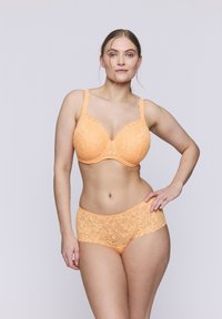 Perzikkleurige kanten bh en bijpassende slipset met bloemenpatronen, golvende randen en verstelbare bandjes. Glad textuur en voorgevormde cups.
