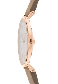 Montre rose gold avec un bracelet en cuir beige mat, cadran blanc minimaliste, profil slim et index des heures en argent. Détail de couronne ajustable.